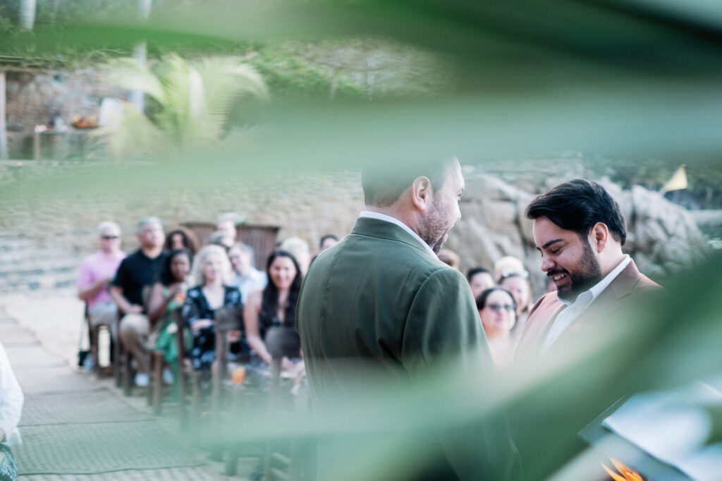 Two grooms sharing a joyful moment during wedding ceremony at Las Caletas, Puerto Vallarta