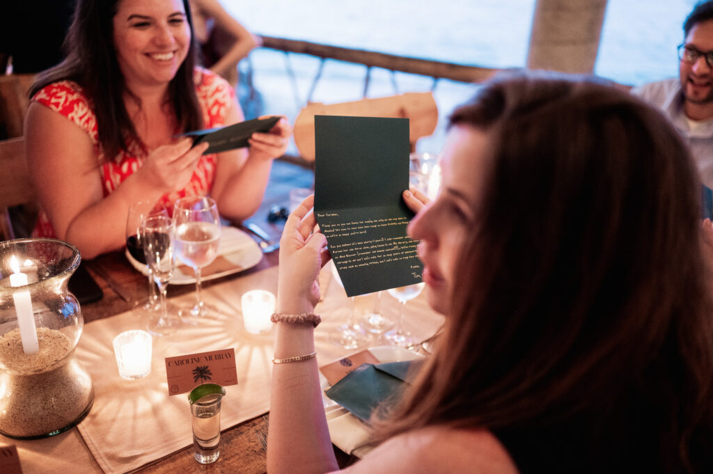 Guest reading a heartfelt letter at candlelit wedding reception, Las Caletas Puerto Vallarta