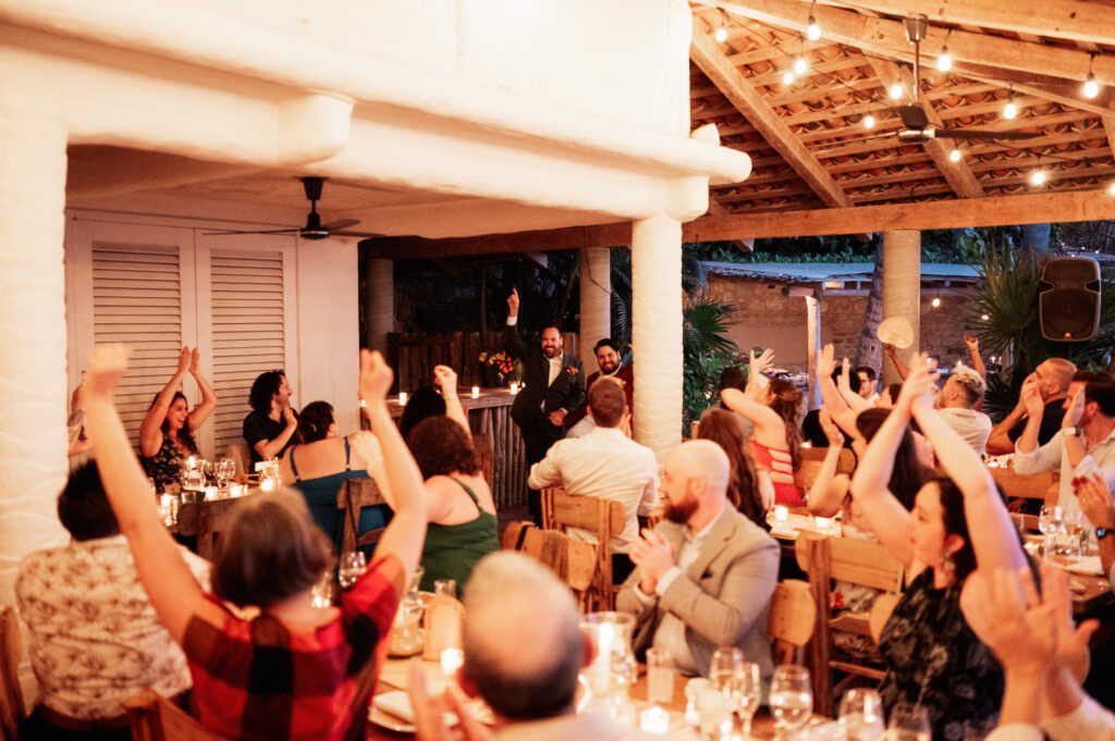 Wedding reception guests cheering at Las Caletas, Puerto Vallarta, candlelit outdoor venue at night