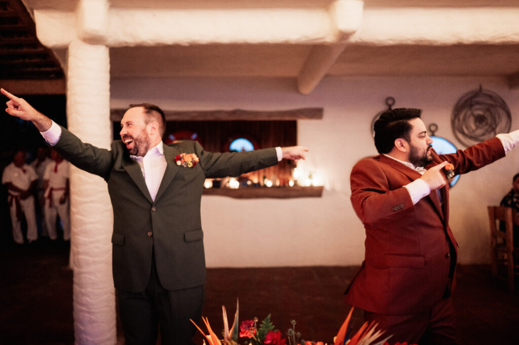 Two grooms dancing joyfully at wedding reception, Las Caletas Puerto Vallarta, documentary wedding photo
