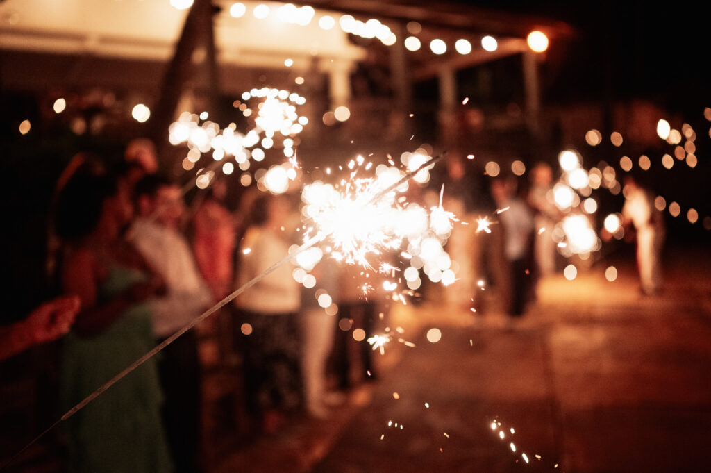 Sparkler moment at Las Caletas wedding reception, Puerto Vallarta, with guests glowing in the background at night