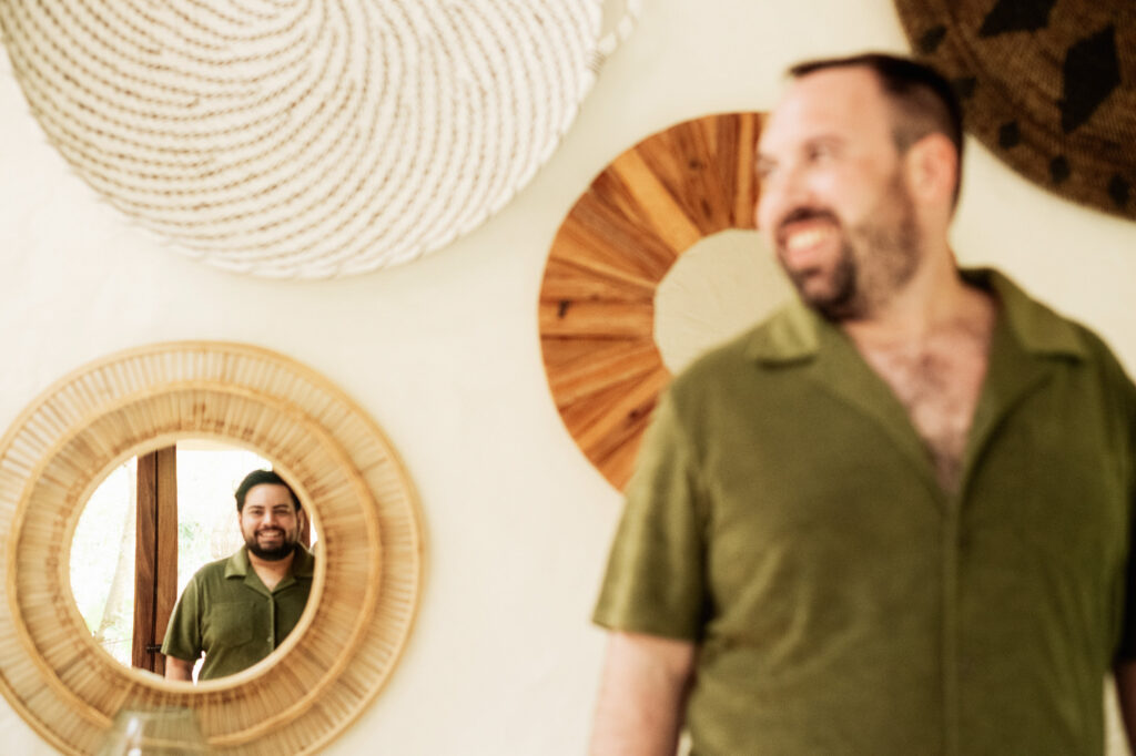 Groom smiling at his reflection in a rattan mirror at Las Caletas, Puerto Vallarta wedding