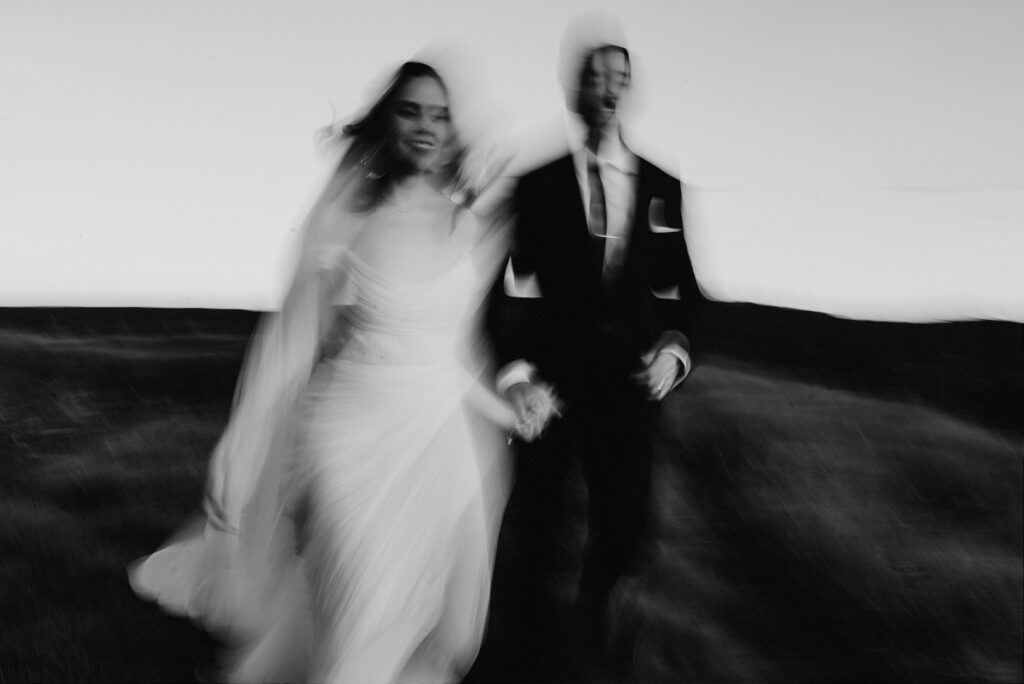 Bride and groom running and laughing at Sierra de Lobos wedding, motion blur black and white film photo