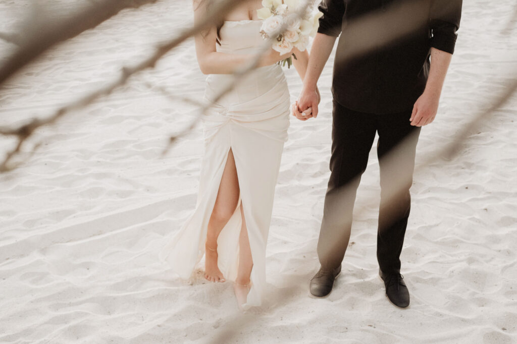 Bride and groom holding hands on white sand beach at St Regis Punta Mita wedding ceremony