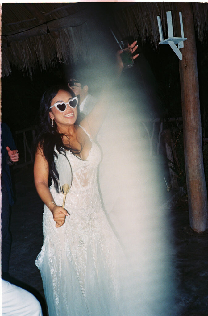 Bride dancing in white gown and heart sunglasses at Villa Valentin reception, Sayulita, shot on 35mm film
