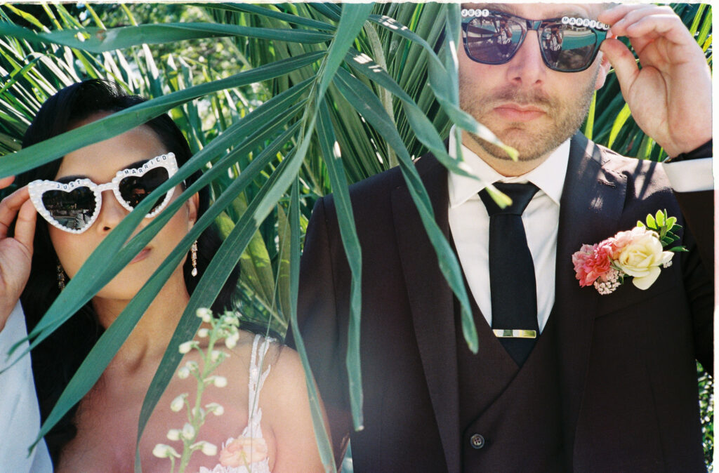 Just Married couple in sunglasses peeking through tropical palms at Villa Valentin Sayulita wedding