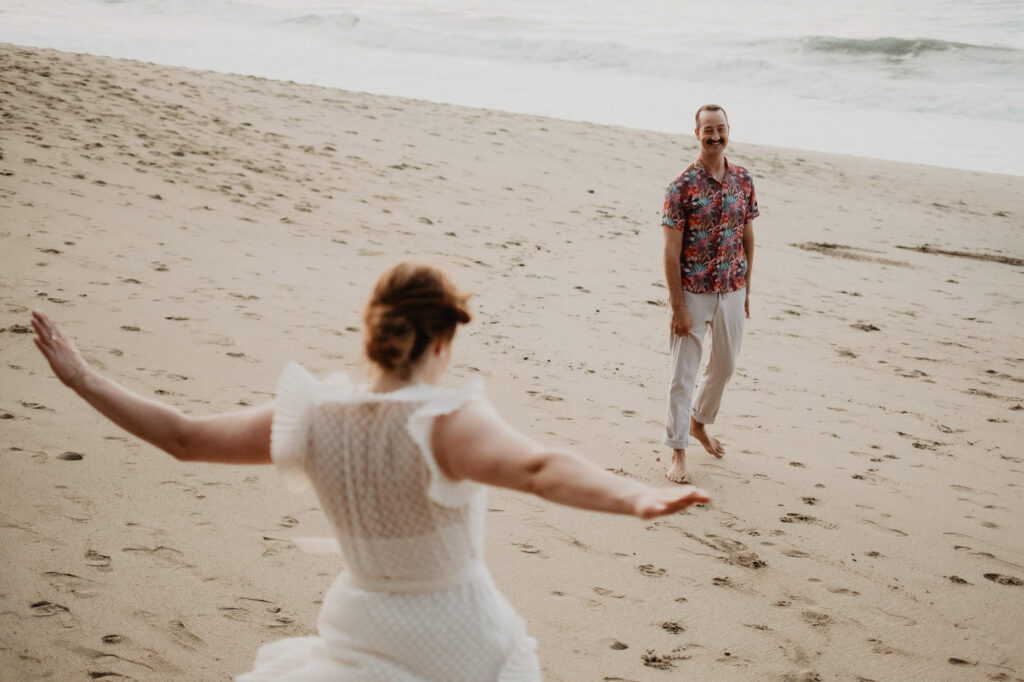Couple running toward each other on Sayulita beach during engagement session, shot on film