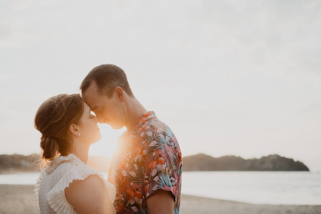 Couple sharing a forehead touch at golden hour on Sayulita beach, engagement session by Alex Obregón