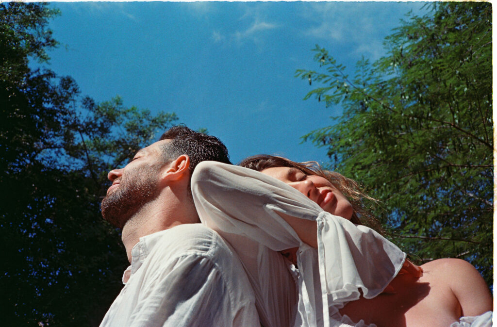Couple leaning back-to-back outdoors in Puerto Vallarta engagement session shot on 35mm film