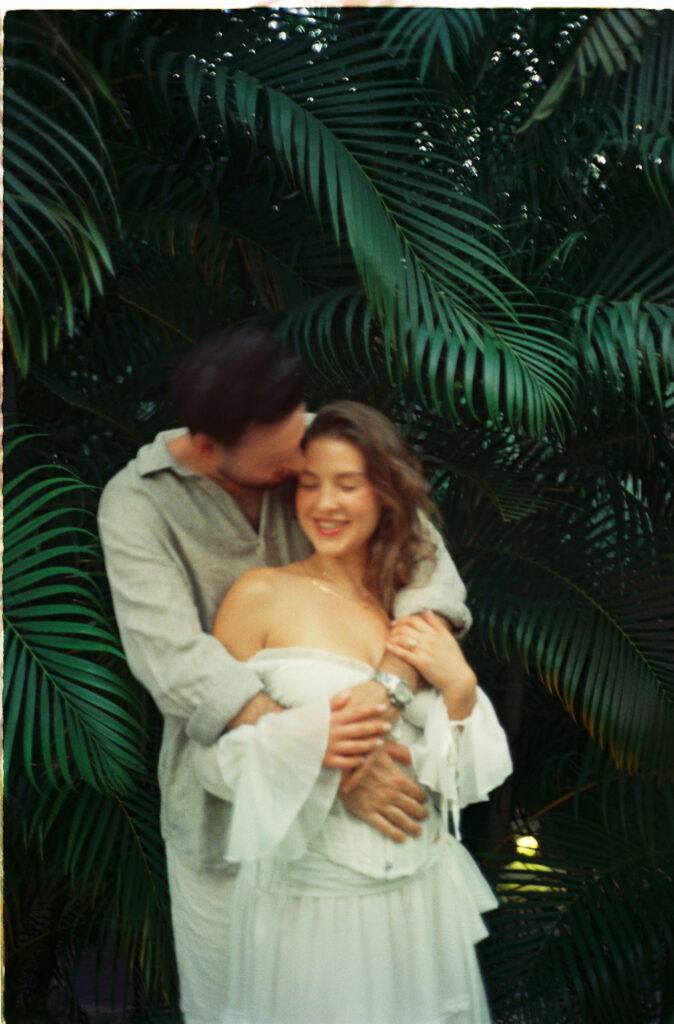 Couple embracing among tropical palms during engagement session in Puerto Vallarta, shot on 35mm film