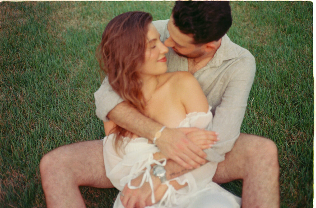 Couple embracing on green grass during engagement session in Puerto Vallarta, shot on 35mm film