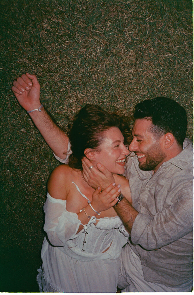 Couple laughing together on hay bale during engagement session in Puerto Vallarta, shot on 35mm film