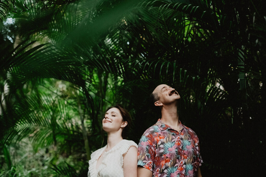 Couple laughing among tropical palms during engagement session in Sayulita, Mexico, shot on film