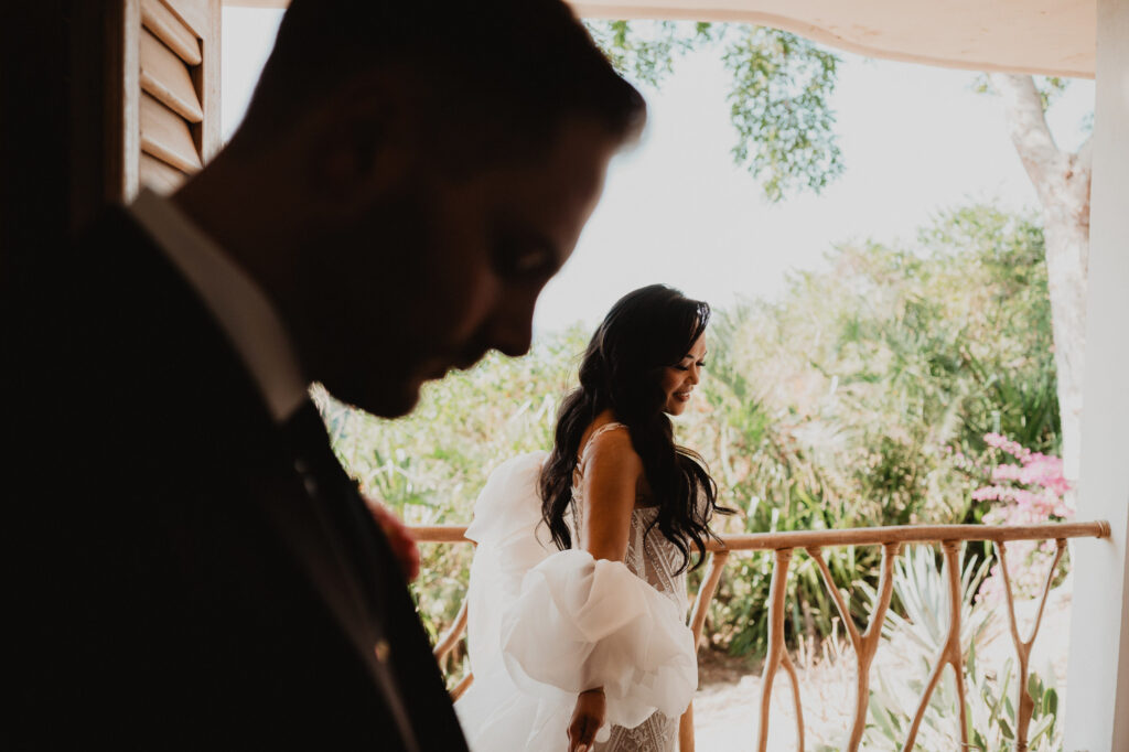 Bride in white gown smiling on balcony at Villa Valentin Sayulita wedding, groom in foreground