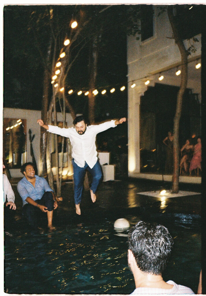 Groom jumping into pool at night wedding reception, Tulum, shot on 35mm film by Alex Obregón