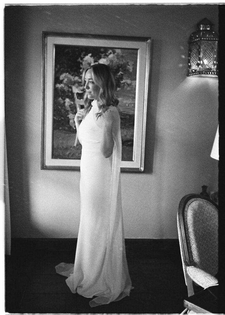 Bride in elegant white gown standing before a painting, San Miguel de Allende wedding, film photography