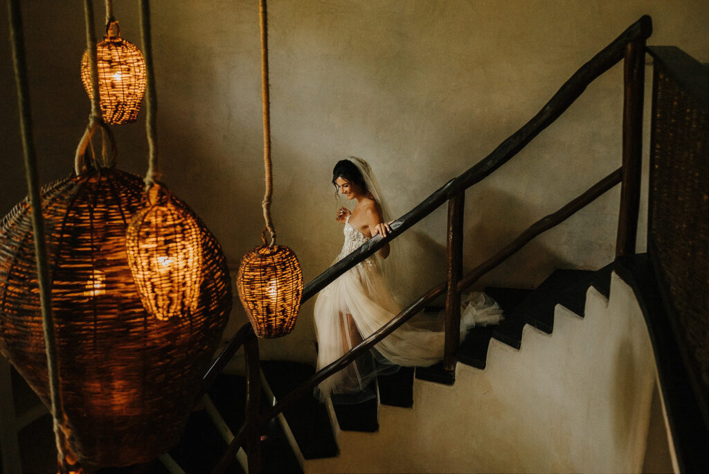 Bride descending candlelit staircase at Papaya Playa Project, Tulum, surrounded by woven lanterns
