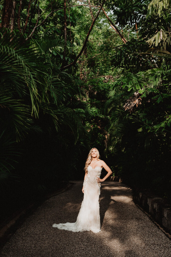 Bride in lace gown smiling on jungle path at One&Only Mandarina elopement, Mexico