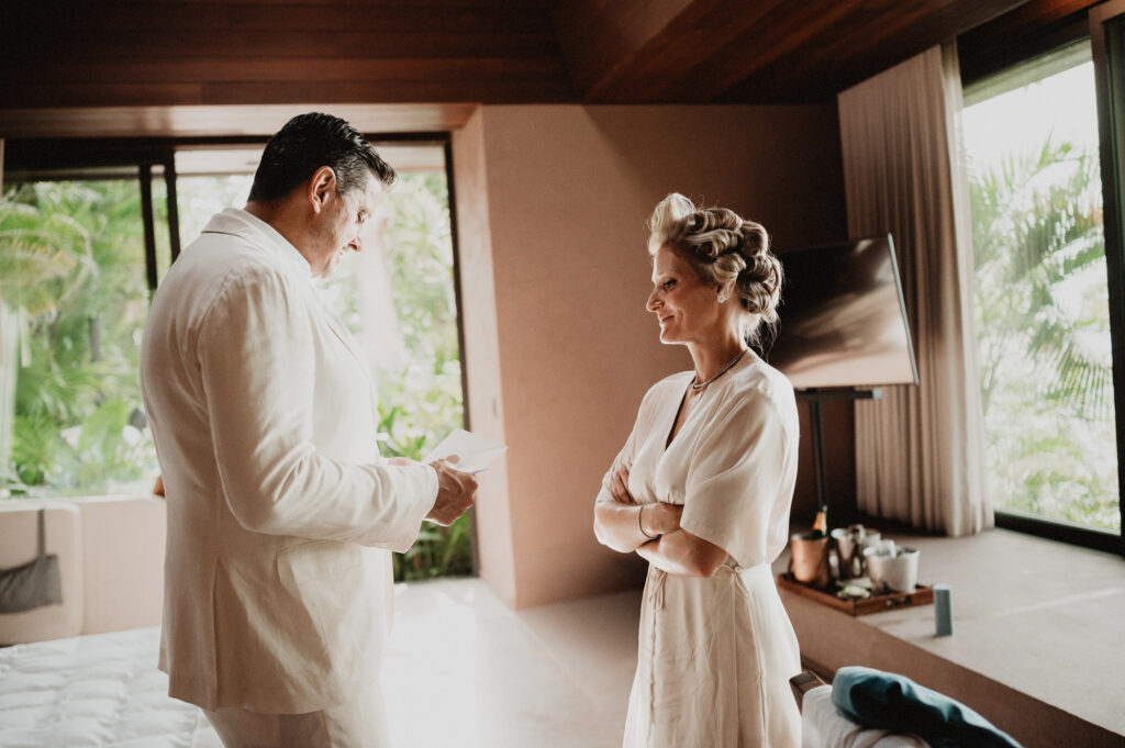 Groom reads vows aloud to smiling bride during elopement at One&Only Mandarina, Mexico