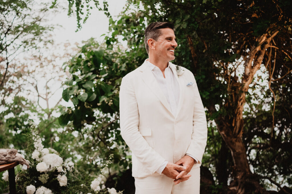 Groom in white linen suit smiling at altar, elopement wedding at One&Only Mandarina, Mexico