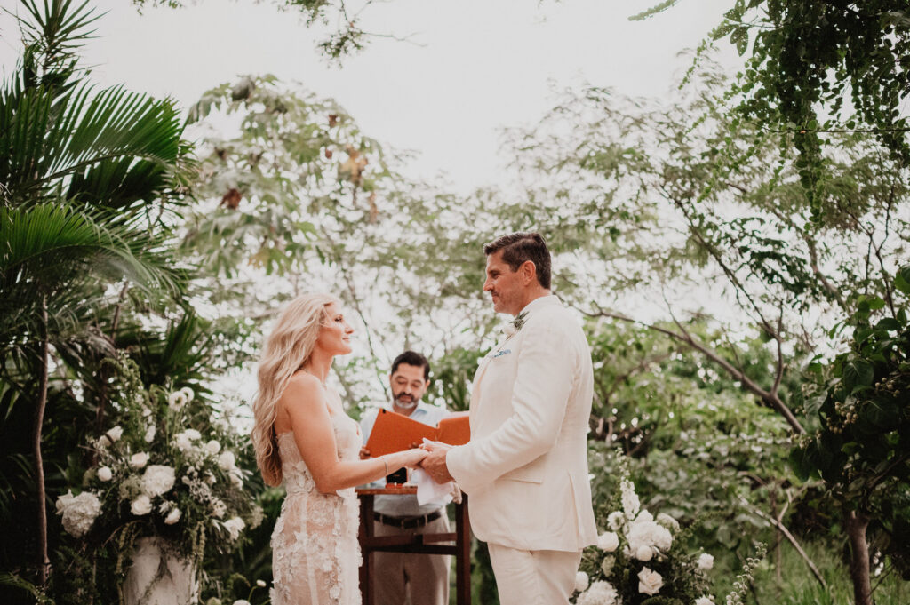Elopement ceremony at One&Only Mandarina, couple exchanging rings outdoors surrounded by tropical greenery and white flowers