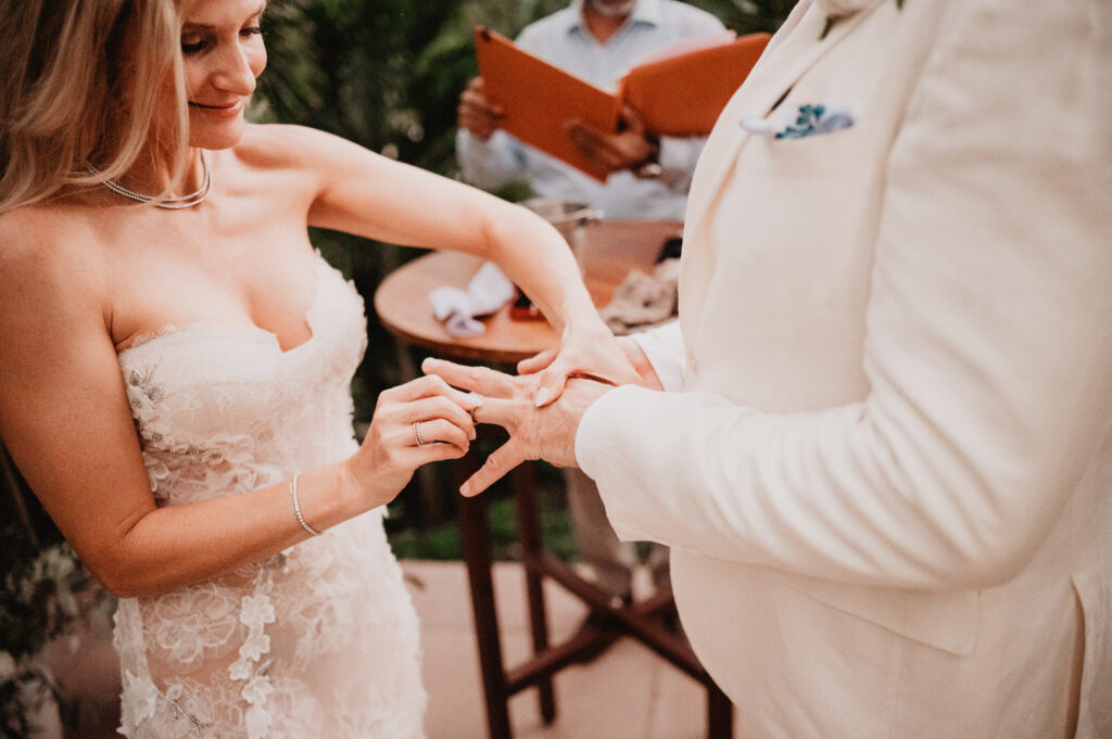 Bride placing wedding ring on groom's finger during elopement ceremony at One&Only Mandarina, Mexico