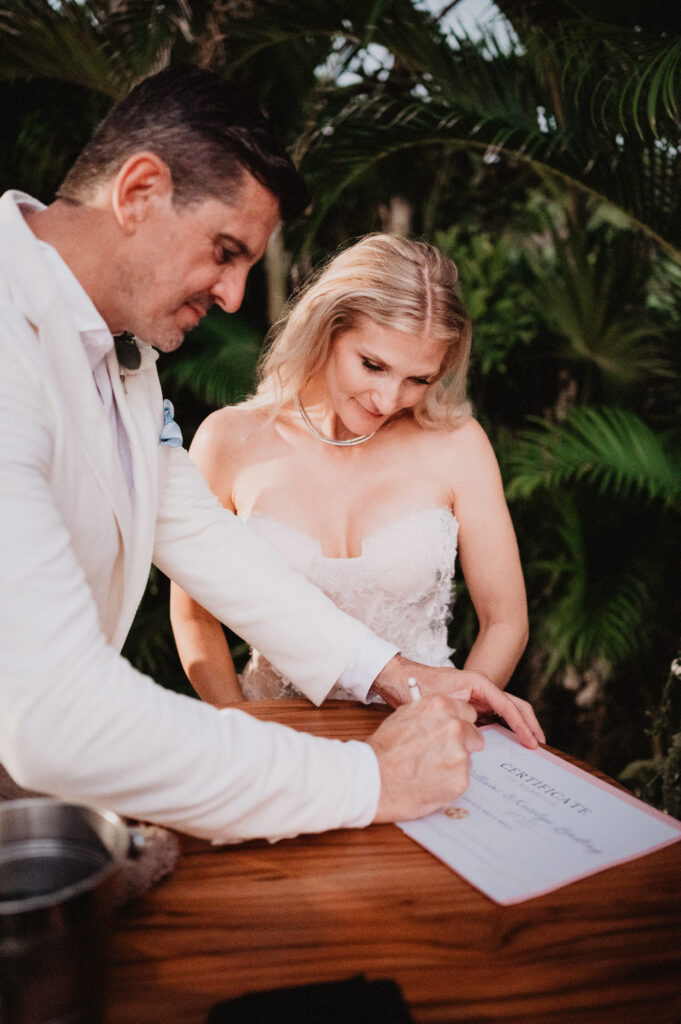 Couple signing marriage certificate during elopement at One&Only Mandarina, Mexico, surrounded by tropical palms