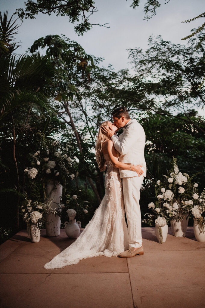 Bride and groom share first kiss at One&Only Mandarina elopement, surrounded by white florals