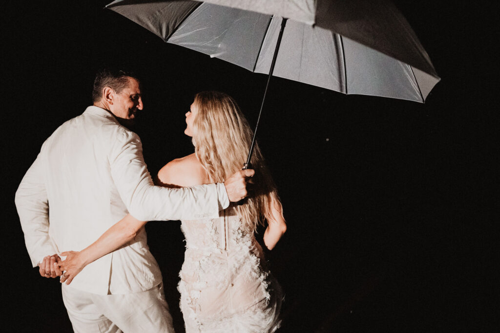 Bride and groom sharing umbrella at night, elopement wedding at One&Only Mandarina, Mexico