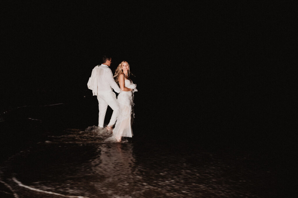 Bride and groom wading into ocean at night, elopement at One&Only Mandarina, Mexico