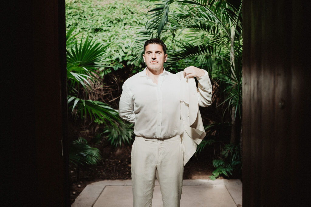 Groom in white linen suit at One&Only Mandarina elopement, tropical greenery backdrop, Mexico
