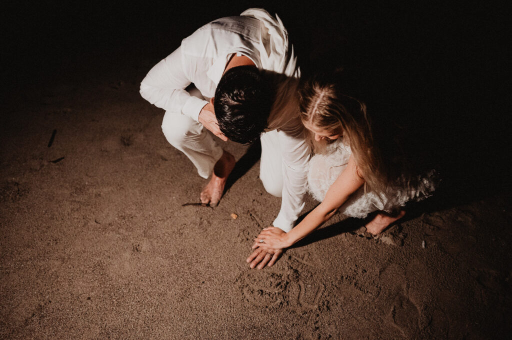 Couple writing in sand at night during elopement at One&Only Mandarina, Mexico, shot by Alex Obregón