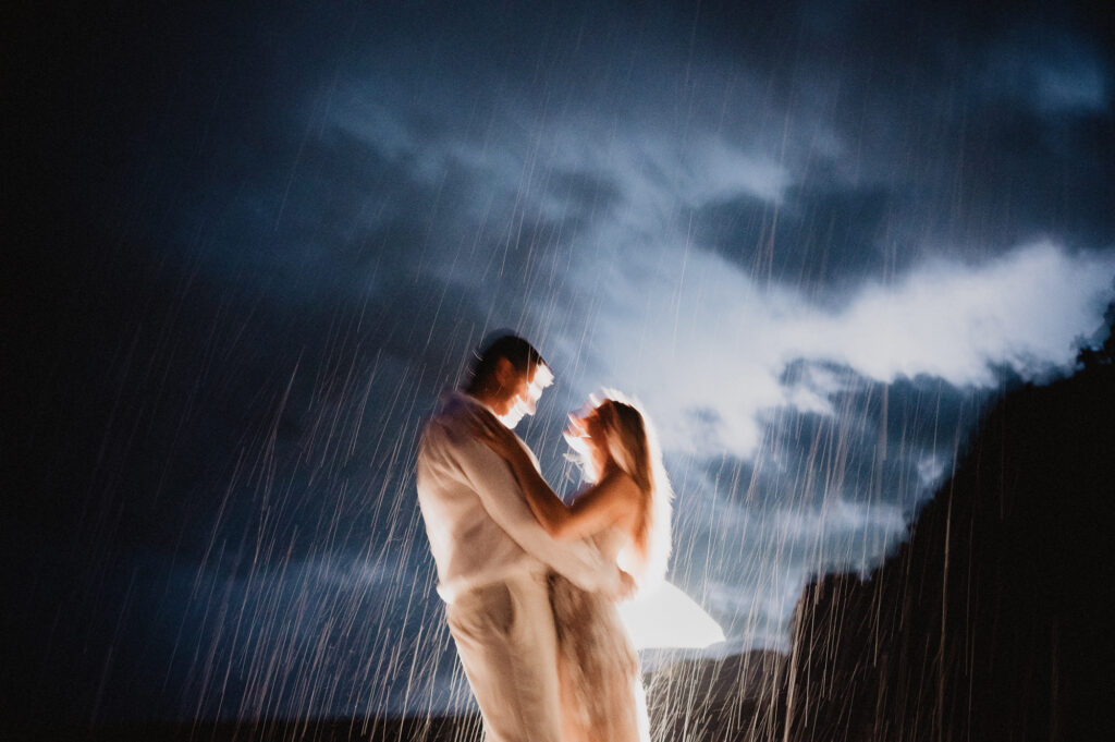 Couple dancing in the rain at night during elopement at One&Only Mandarina, Mexico, lit by warm backlight