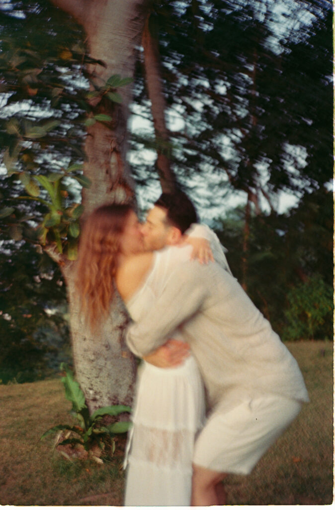 Couple kissing by a palm tree during engagement session in Puerto Vallarta, shot on 35mm film