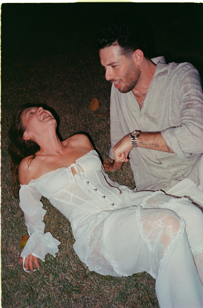 Couple laughing together on grass at night, engagement session in Puerto Vallarta by photographer Alex Obregón