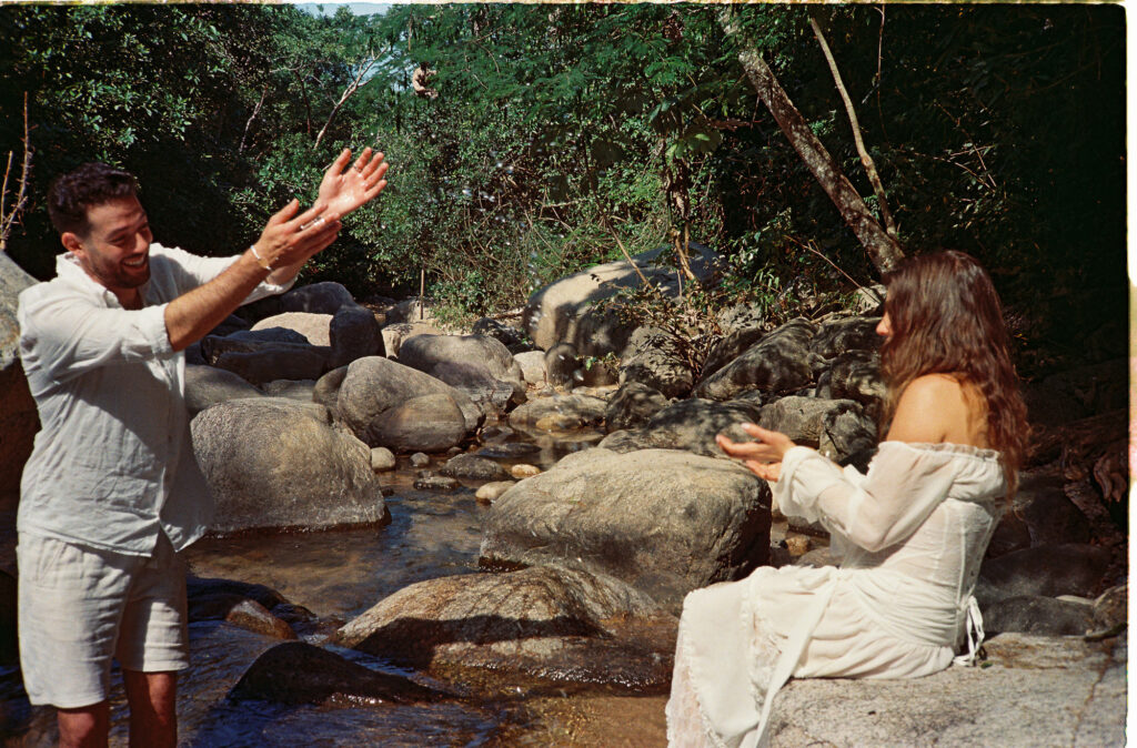 Couple laughing by rocky stream in Puerto Vallarta, analog film engagement session by Alex Obregón