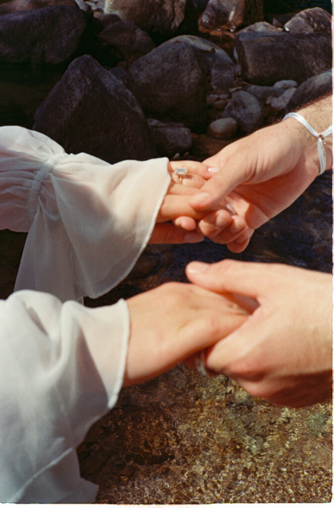 Couple holding hands on rocky Puerto Vallarta shore, engagement session on 35mm film by Alex Obregón