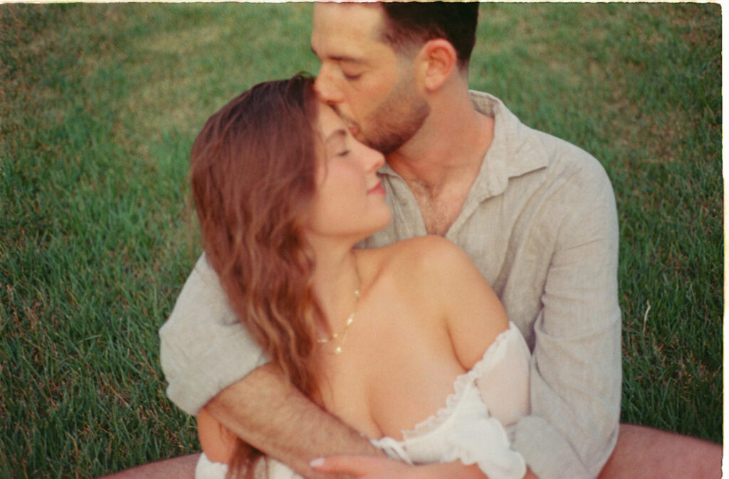 Couple embracing on green grass during engagement session in Puerto Vallarta, shot on 35mm film