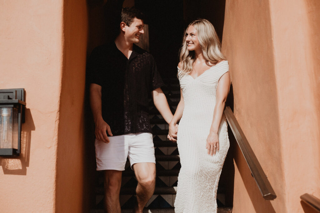 Couple holding hands and smiling on stone steps at Casa Cosmos, Puerto Vallarta engagement session