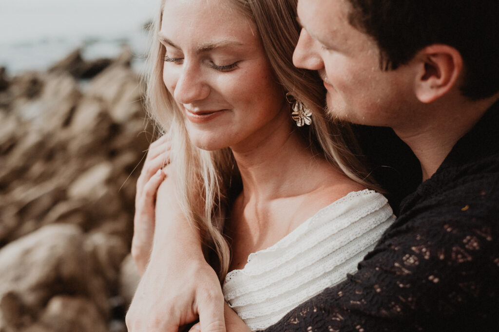 Couple embracing on rocky shore at Casa Cosmos Puerto Vallarta, engagement session by Alex Obregón