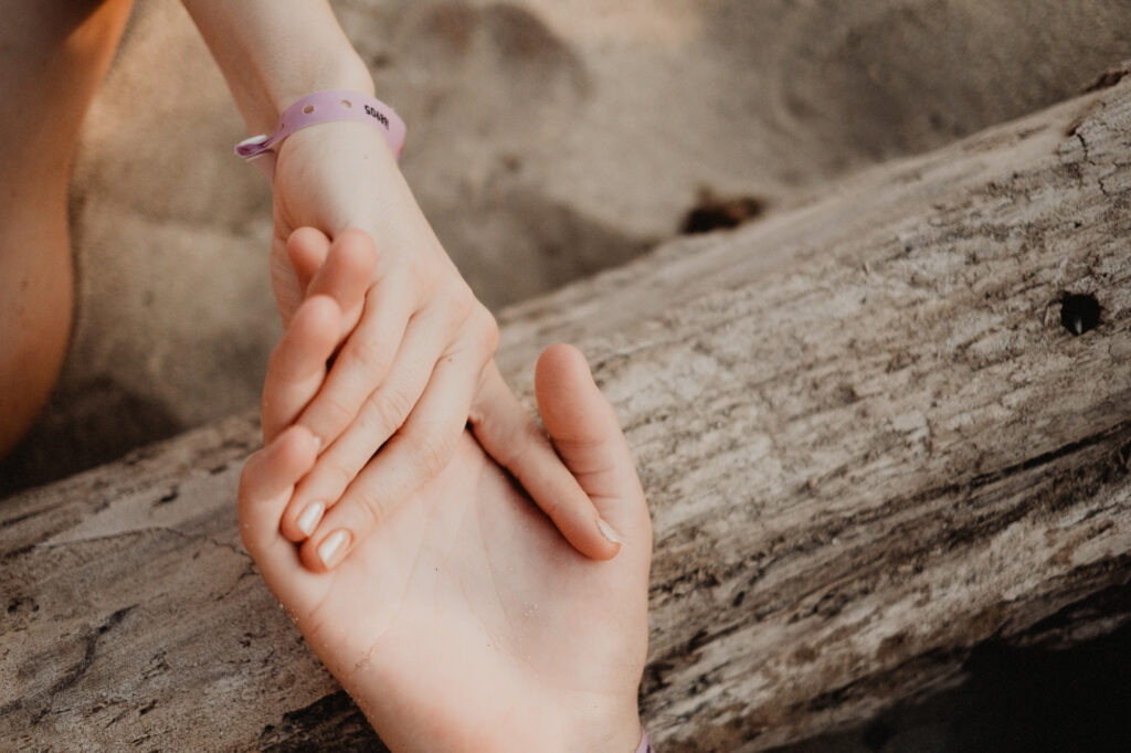 Two hands holding gently on driftwood at a Puerto Vallarta beach engagement session