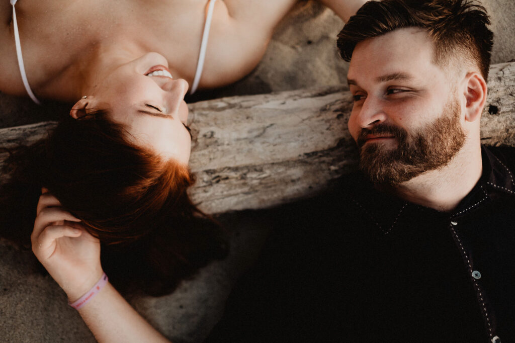Couple laughing together on driftwood during engagement session in Puerto Vallarta