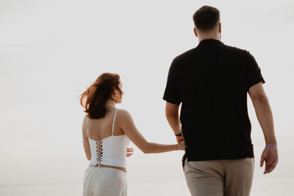 Couple holding hands walking on beach in Puerto Vallarta engagement session by destination wedding photographer