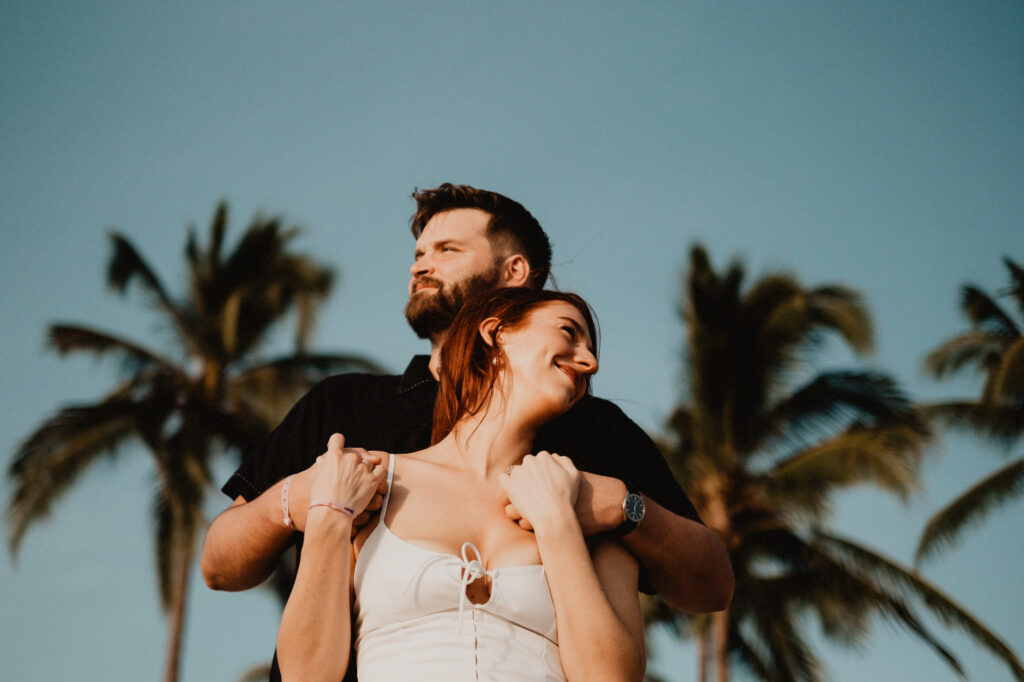 Couple embracing at golden hour with palm trees, engagement session in Puerto Vallarta by Alex Obregón
