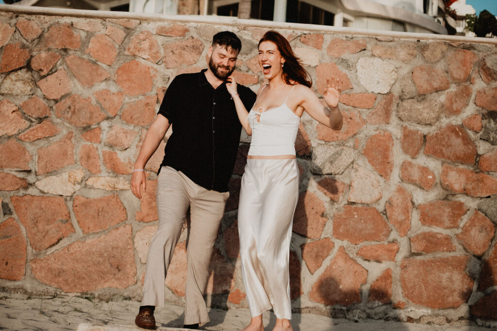 Couple laughing and walking together during engagement session in Puerto Vallarta, Mexico