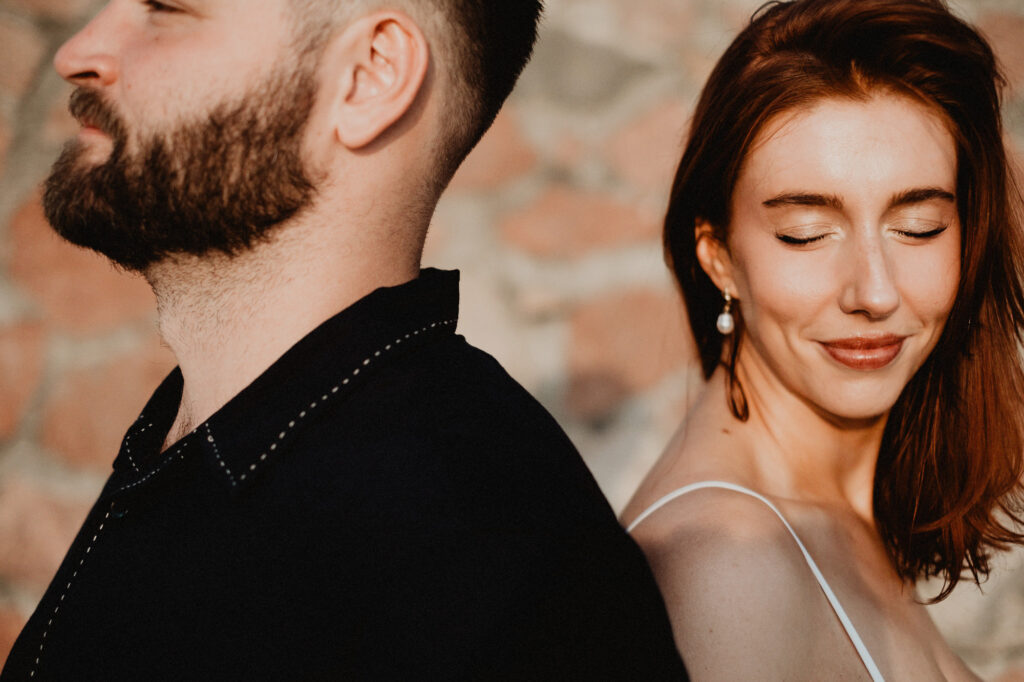 Couple during engagement session in Puerto Vallarta, warm golden light, brick wall background