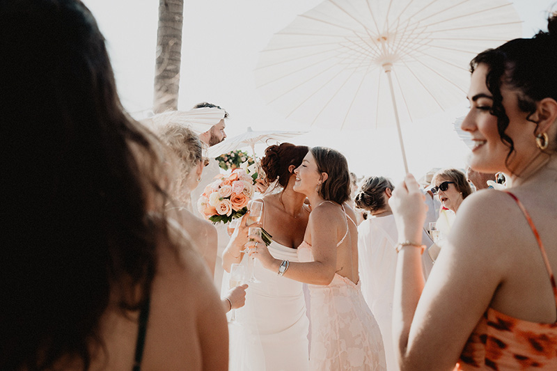 Bride laughing with guests during wedding reception at Riu Vallarta, Puerto Vallarta, holding peach rose bouquet