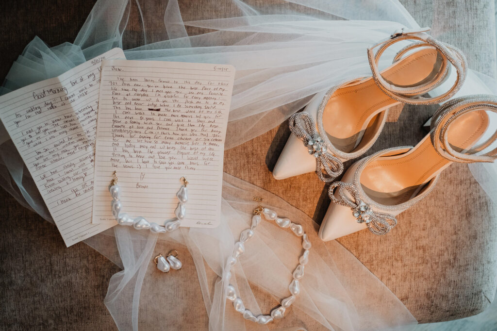 Bridal details flat lay with handwritten vows, pearl jewelry, and heels at Hilton Puerto Vallarta wedding