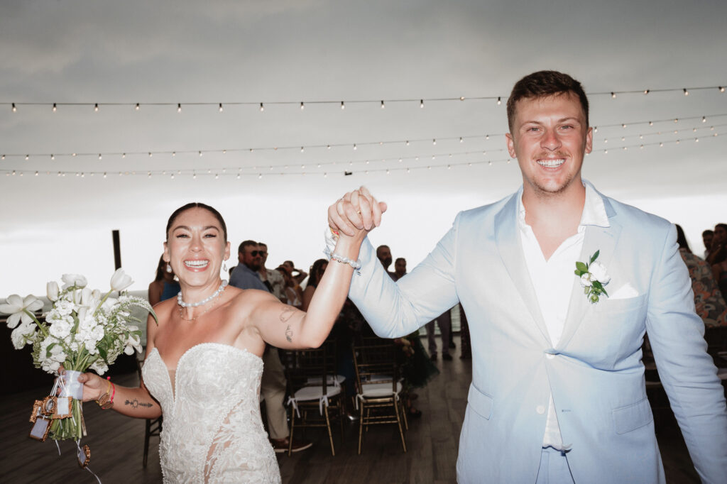 Bride and groom raise hands in joy at Hilton Puerto Vallarta wedding ceremony, documentary style