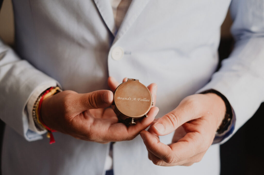 Groom holding engraved compass keepsake at Hilton Puerto Vallarta wedding ceremony, documentary photography